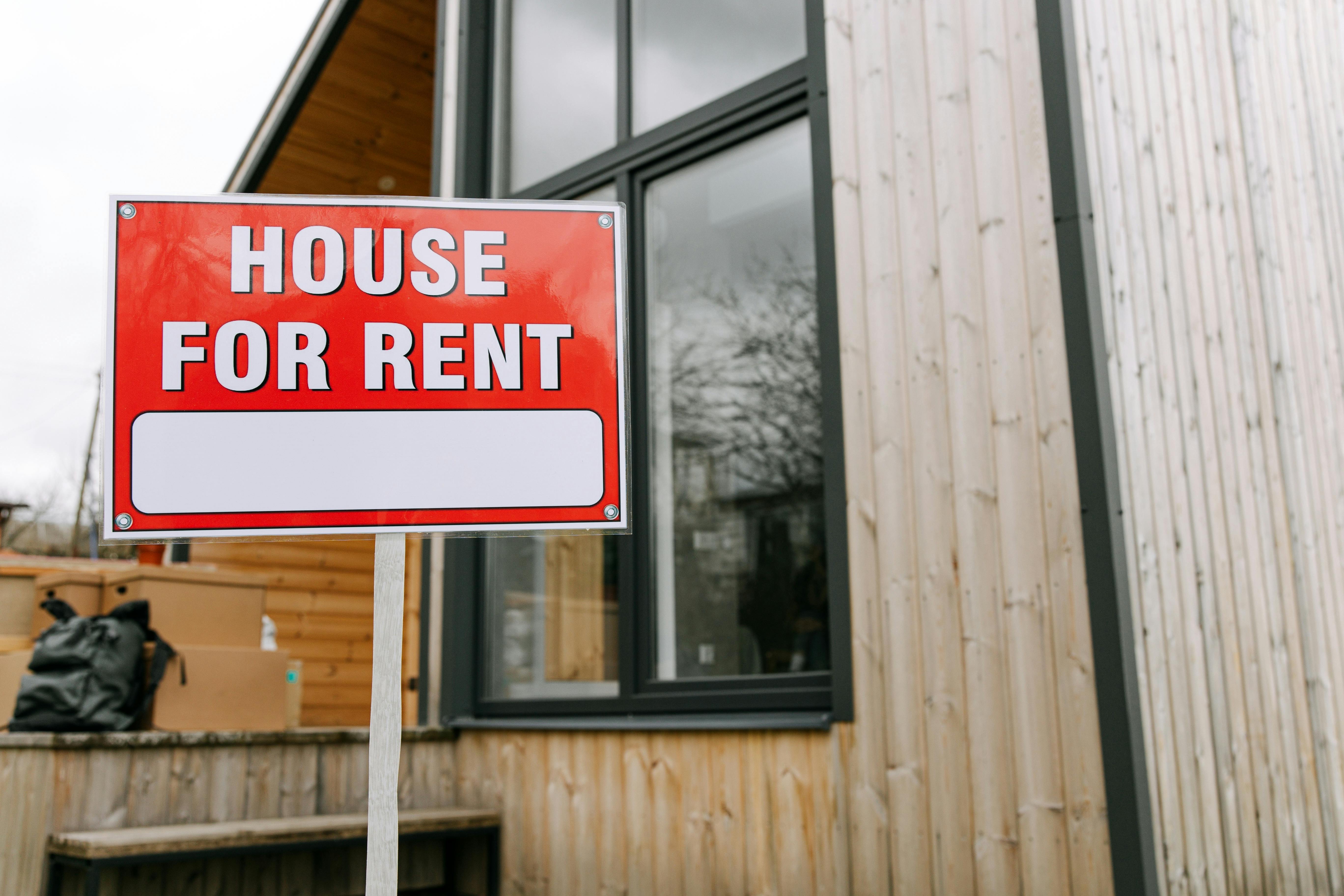 a red house for rent sign put there by a virtual personal assistant for a property management business